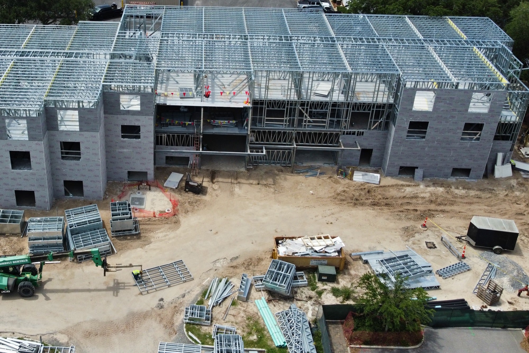 Aerial view of a multi-story building under construction with a steel roof structure